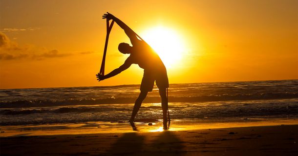 Mann trainiert am Strand vor tiefer Sonne mit Flexvit 