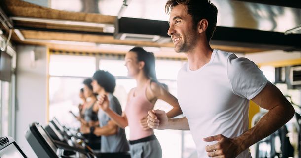 Glückliche Mitglieder im Fitnessstudio auf dem Laufband