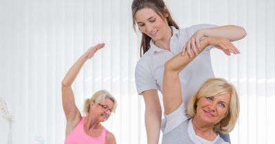 Ältere Damen beim Dehntraining der rechten Körperhälfte mit weiblichem Coach