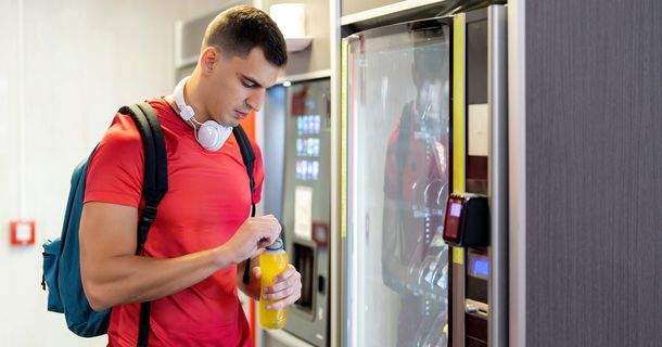 Fitnessstudiomitglied steht an einem Snackautomat