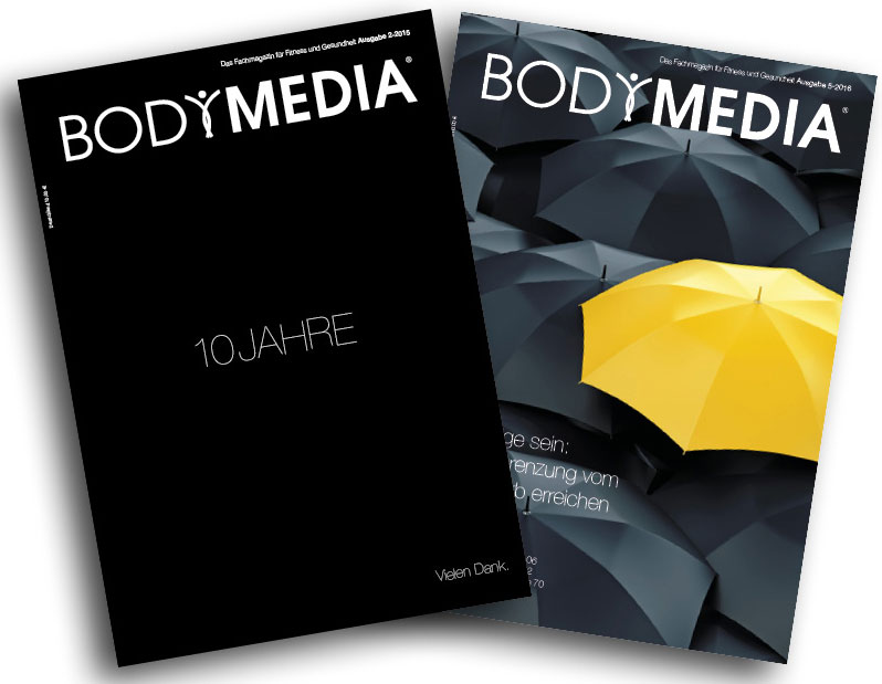 Zwei BODYMEDIA Ausgaben, die eine ist schwarz und die 10 jährige Jubiläumsausgaben und die andere hat auf dem Cover schwarze Regenschirme und einen gelben.