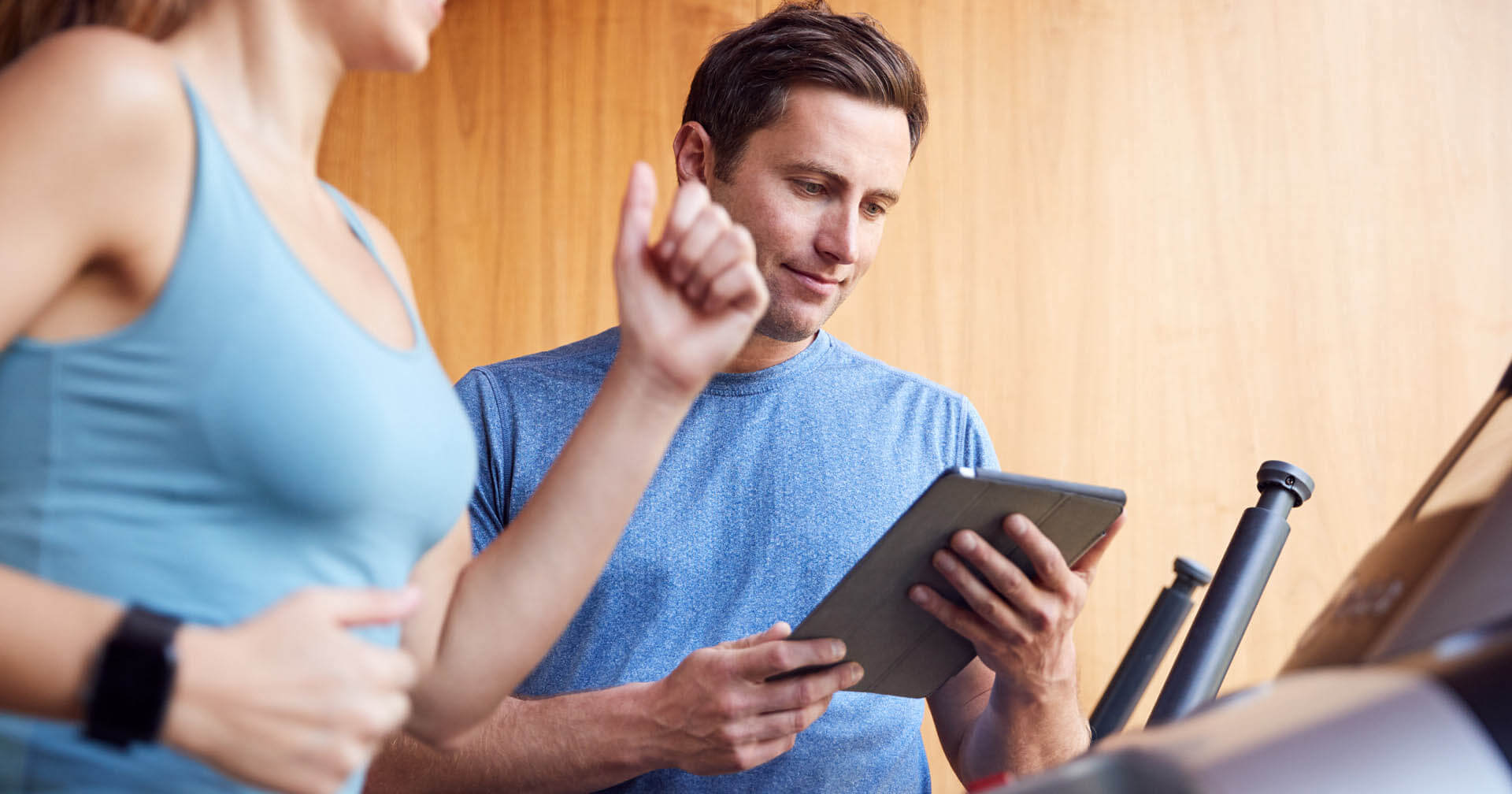 Datenerhebung bei einem Training durch einen Trainer mit laptop während eine Frau auf dem Laufband trainiert