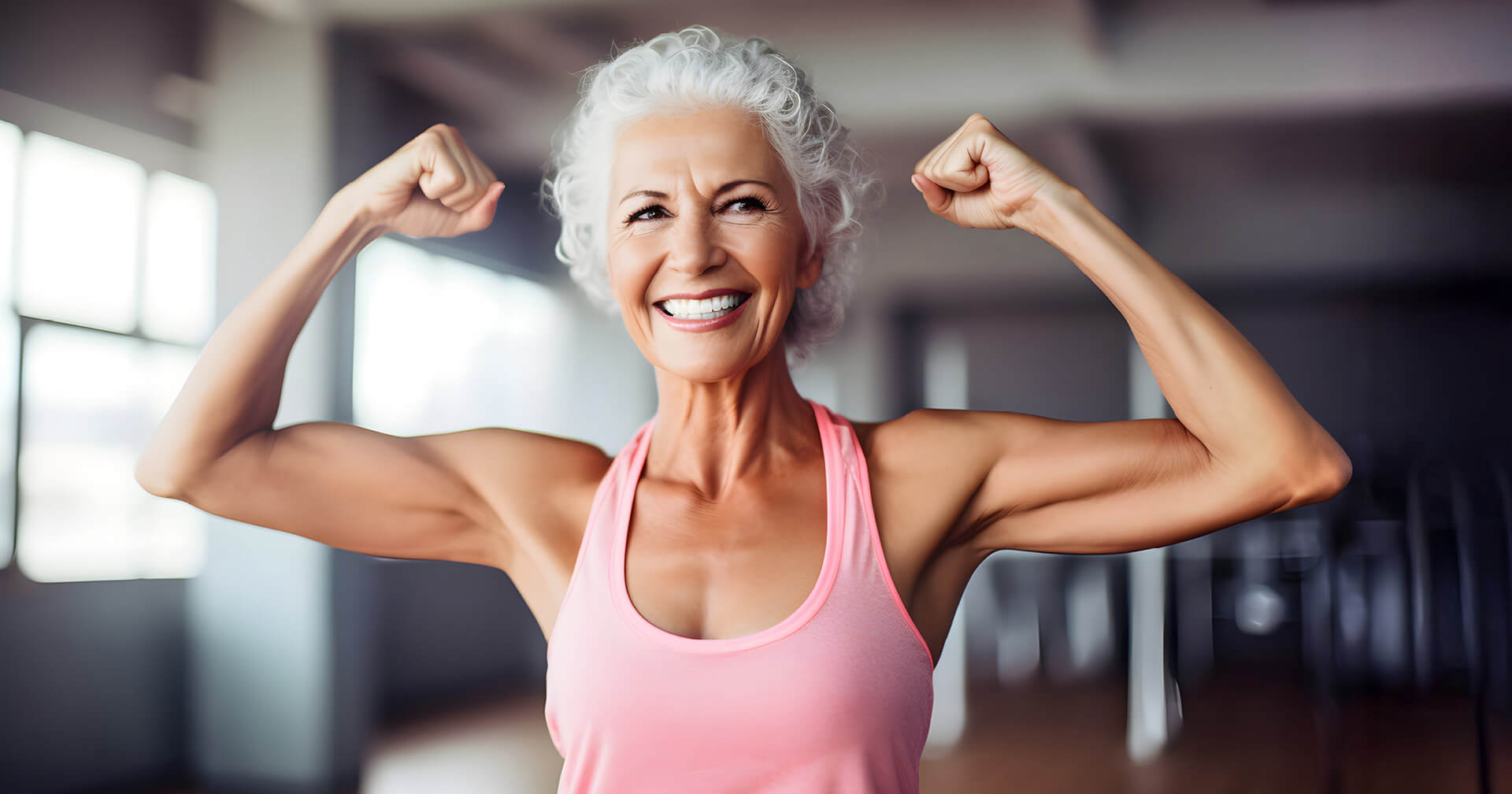 Ältere Frau im Fitnessstudio zeigt ihren Bizeps