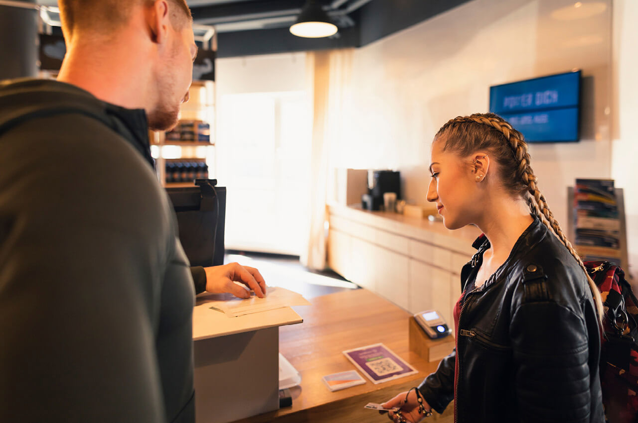 Fitnessstudiomitglied mit Trainer beim Check-In Counter im Fitnessstudio