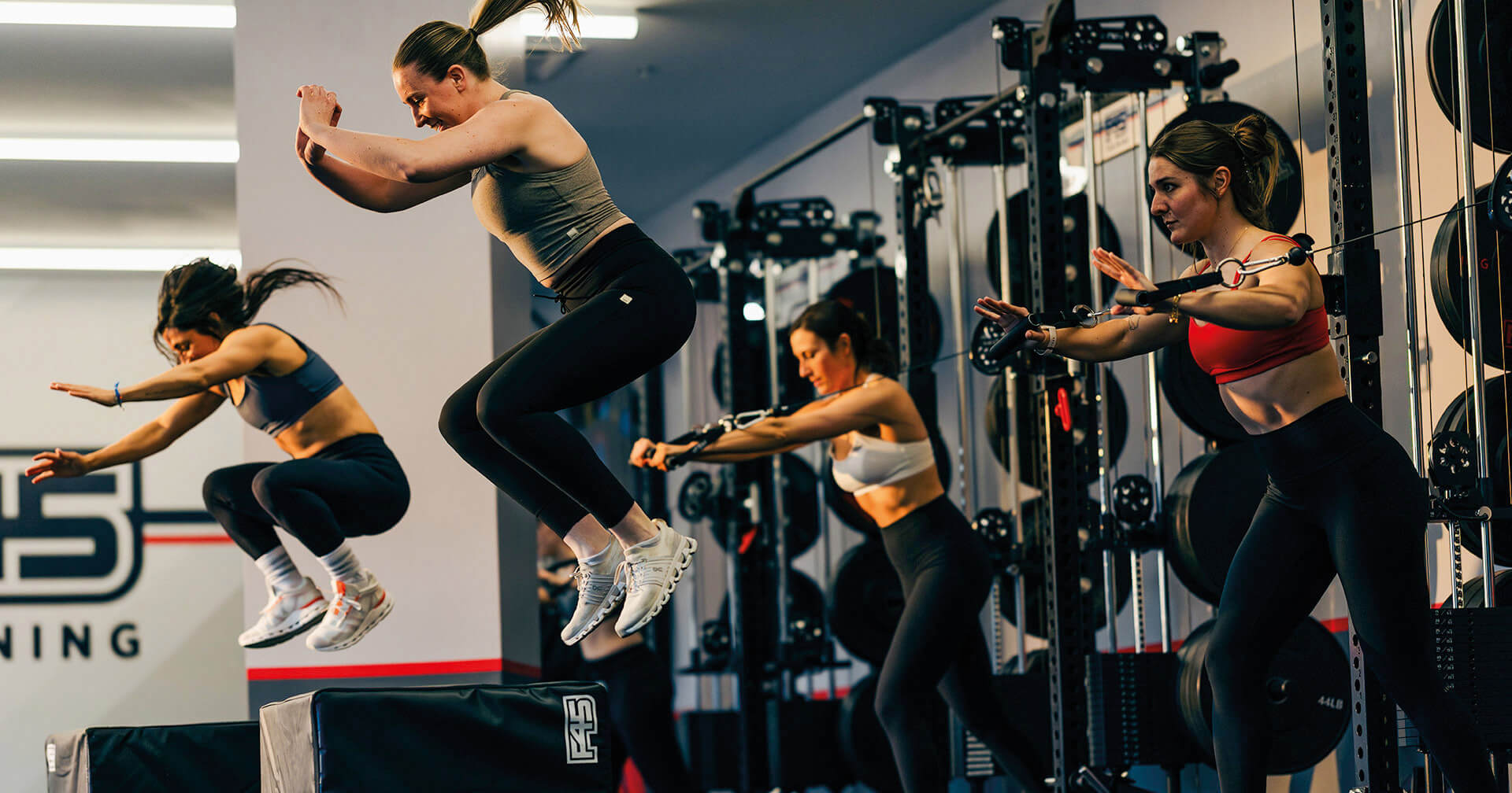 Zwei Frauen springen in einem Gym bei Training auf eine Box