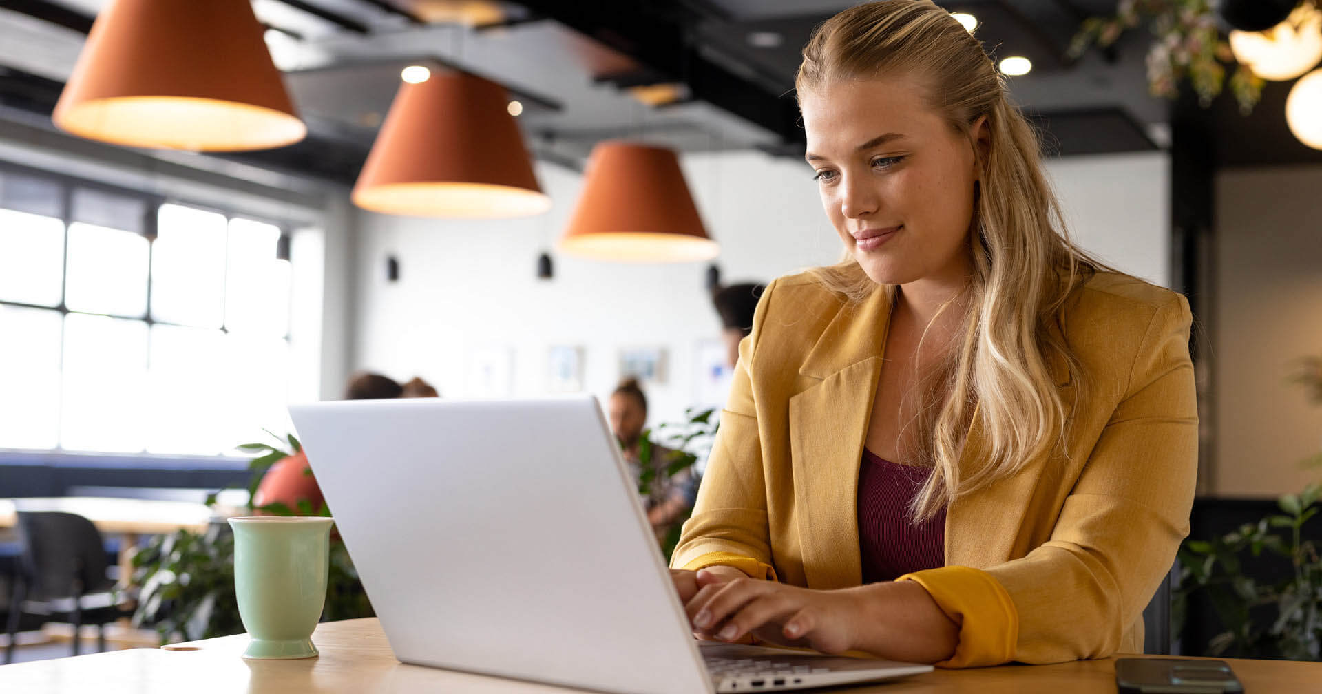 Blonde, lächelnde Frau sitzt vor einem Laptop