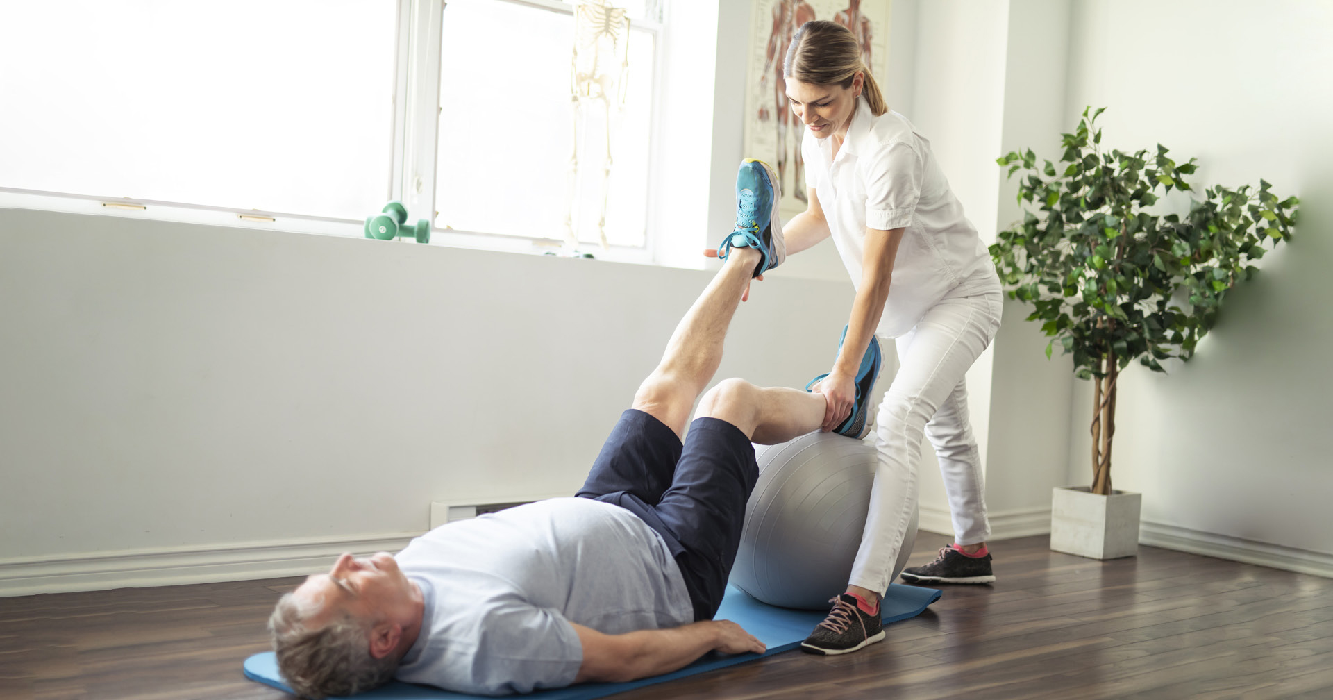 Physiotherapeutin macht eine Beinübung mit ihrem Patient