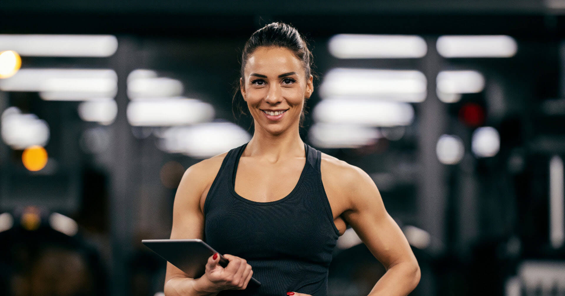 Sportliche Frau mit Tablet im Fitnessstudio