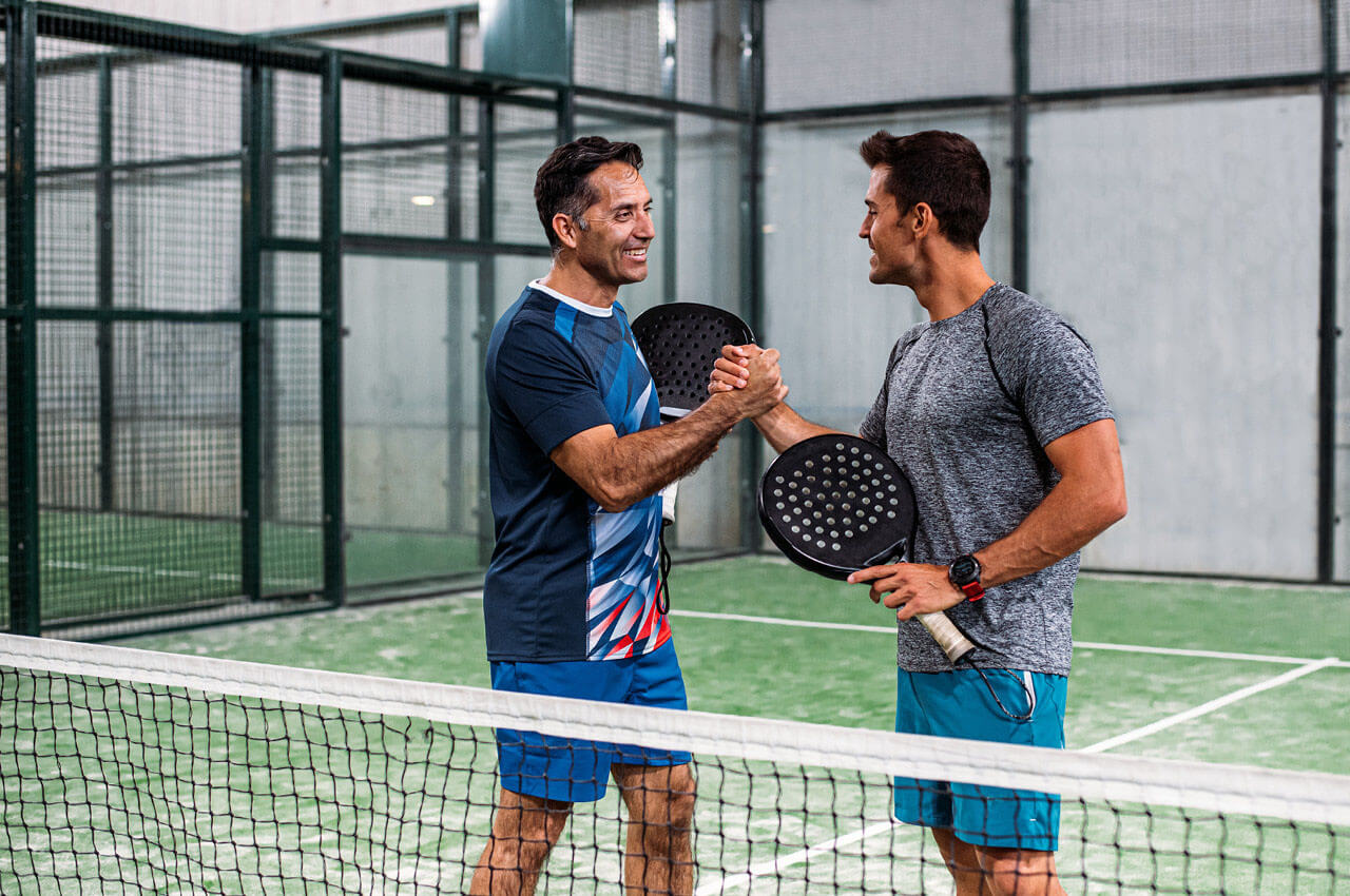 Zwei Padelspieler geben sich auf dem Padelplatz die Hand