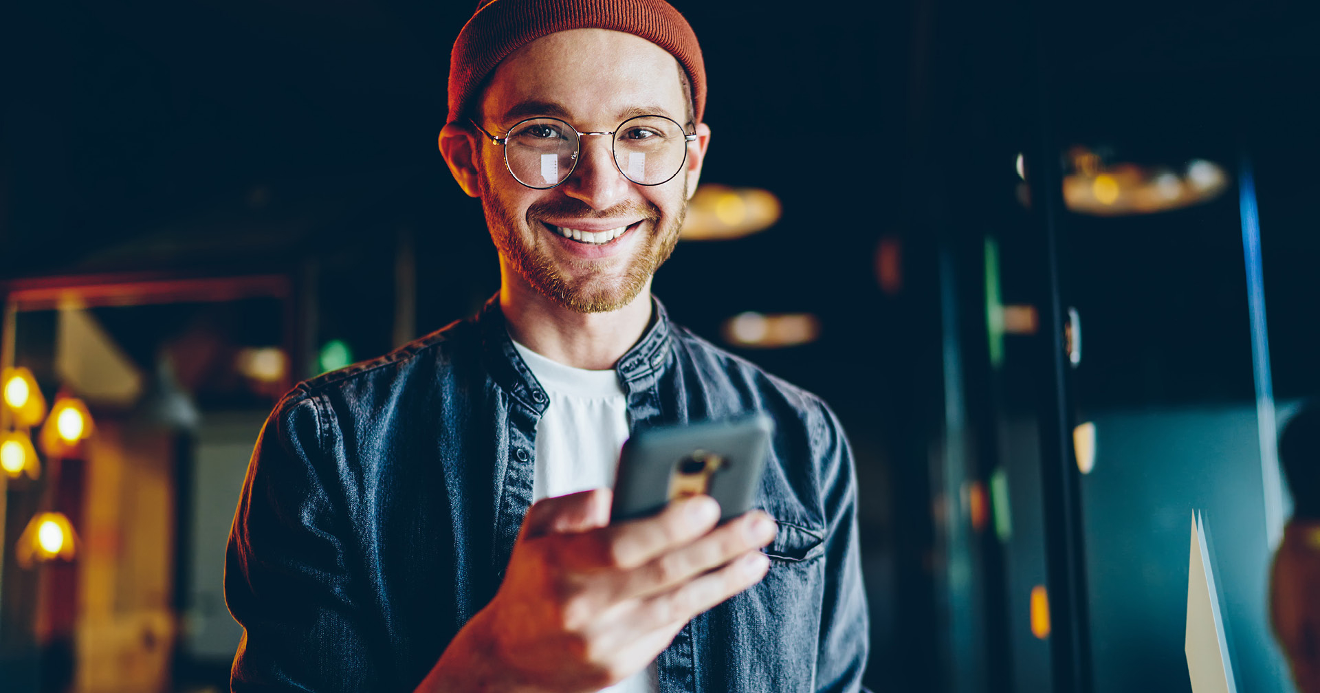 Junger Mitarbeiter tippt etwas in sein Handy ein