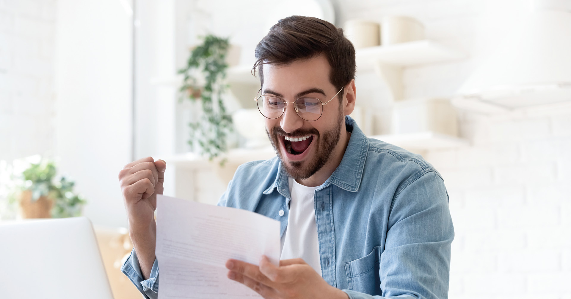 Mann freut sich während er sich ein Blatt Papier durchliest