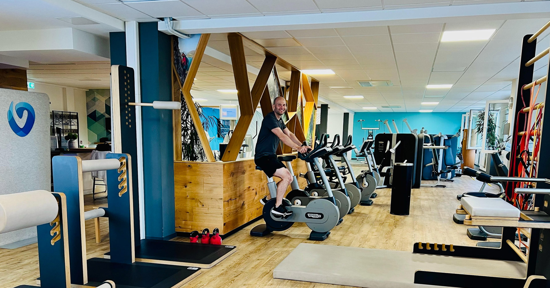 Eine Mitarbeiterin der Vitova Gruppe unterstützt eine trainierende, die auf einem Indoor Cycle sitzt.