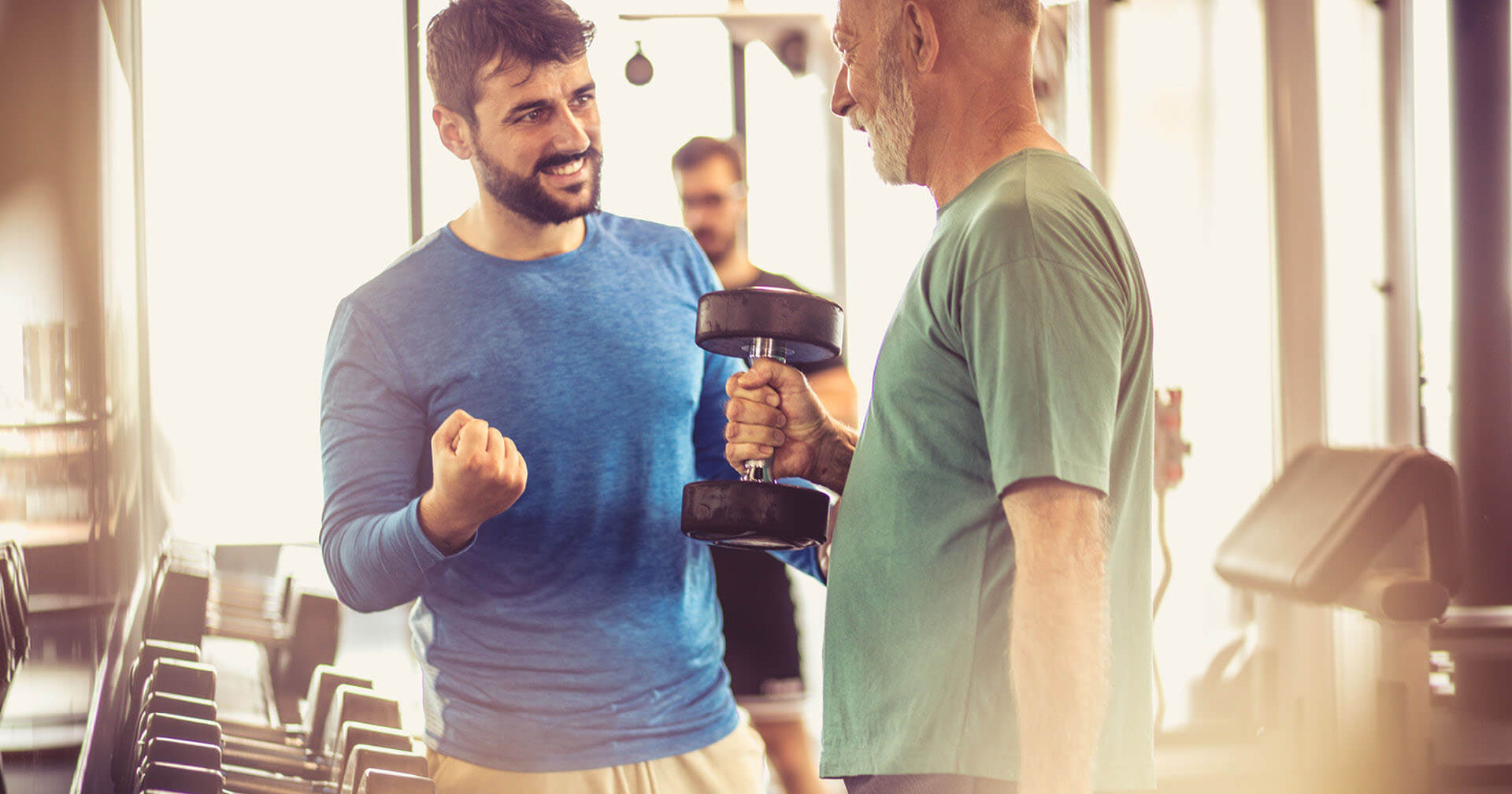 Junger Mann motiviert älteren Mann in einem Fitnessstudio