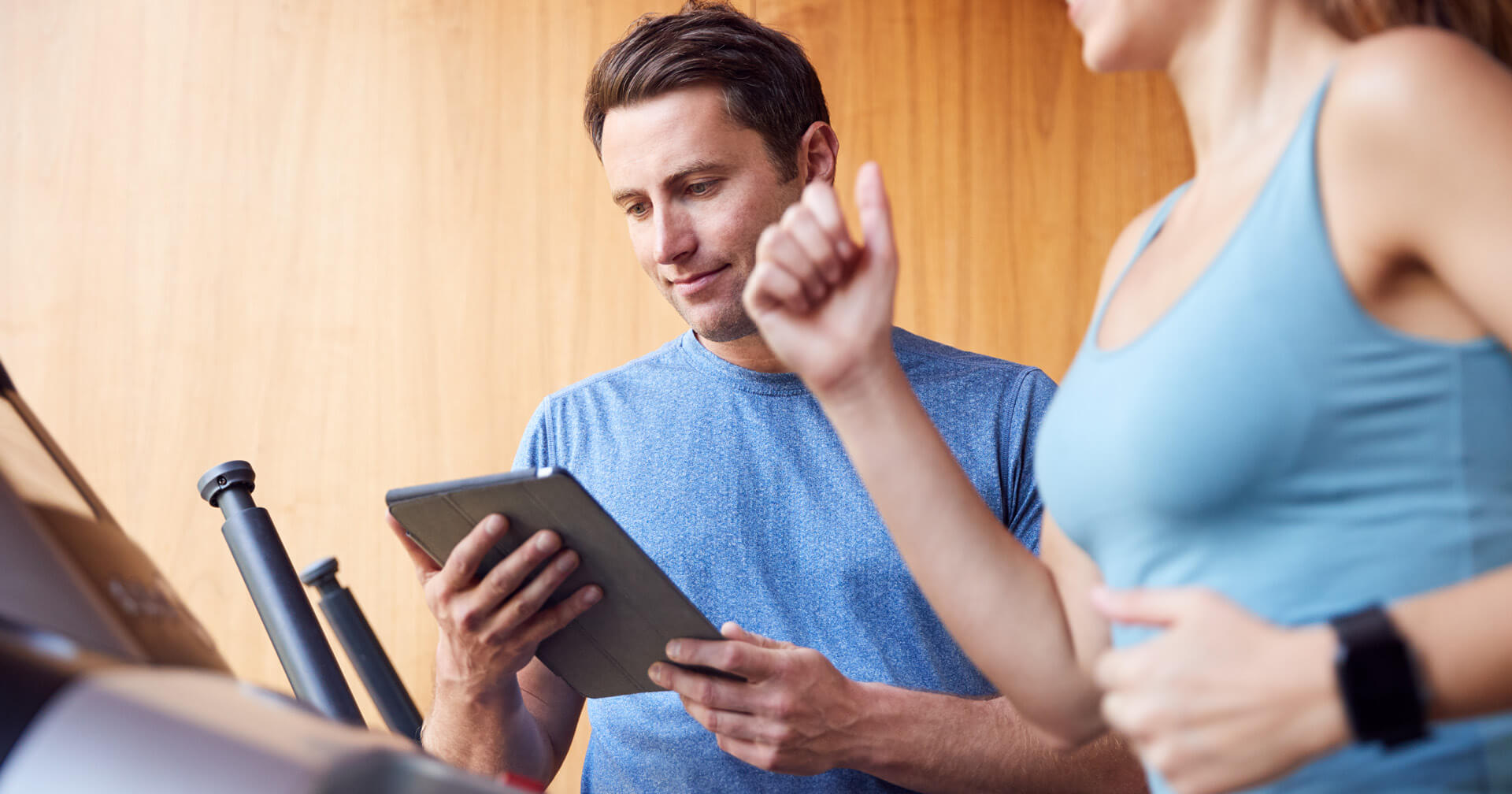 Mann mit Tablet neben einer laufenden Frau auf dem laufband