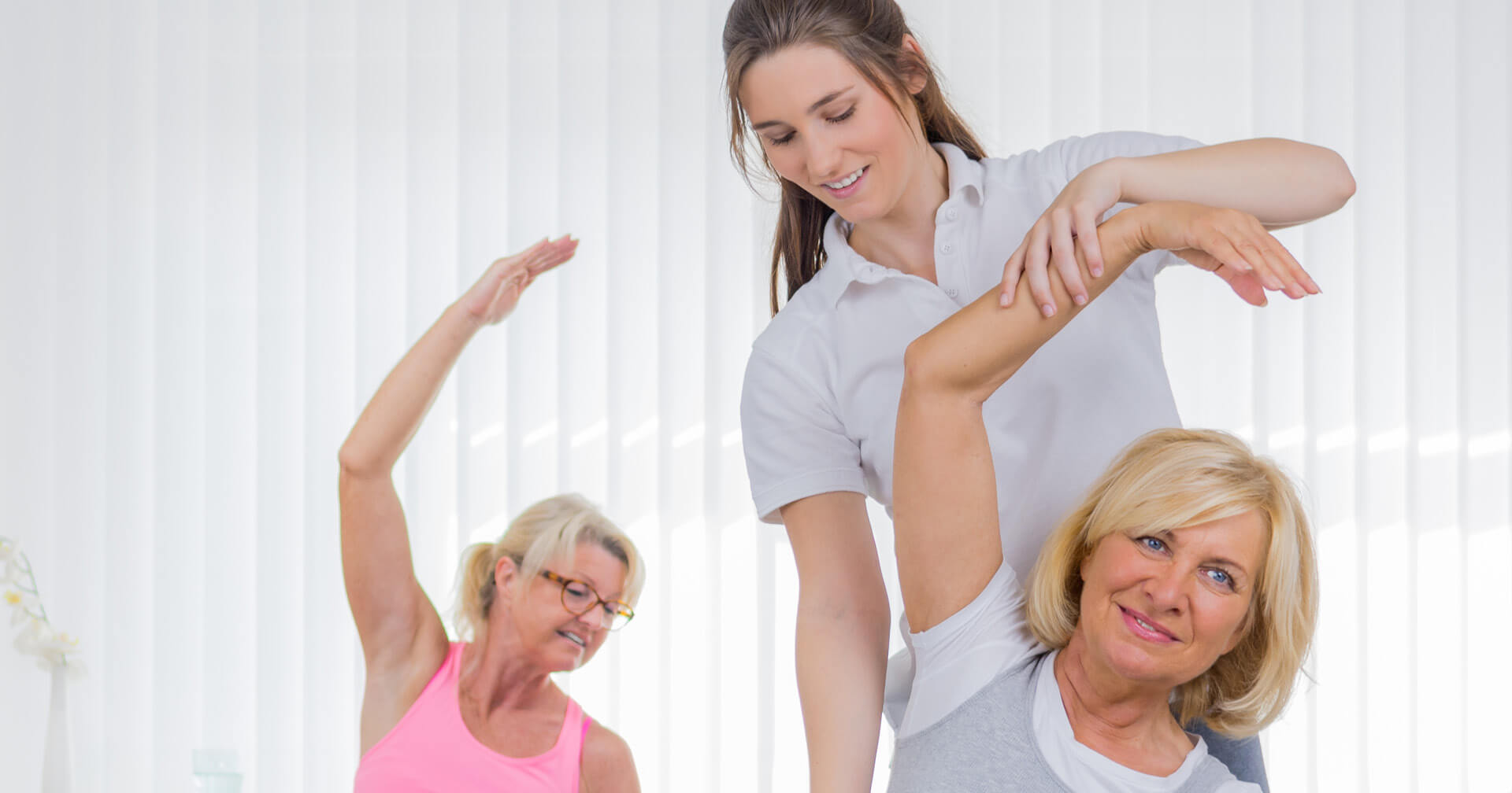 Ältere Damen beim Dehntraining der rechten Körperhälfte mit weiblichem Coach