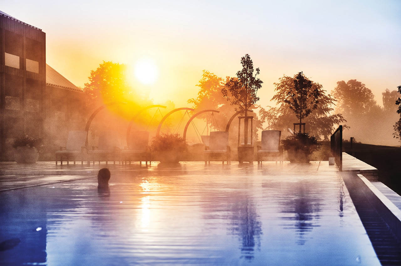 Frau badet im Infinity-Au&szlig;enpool im &Ouml;schberghof w&auml;hrend die Sonne langsam untergeht