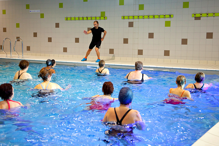 Trainer macht den Kursteilnehmern im Wasser Übungen vor