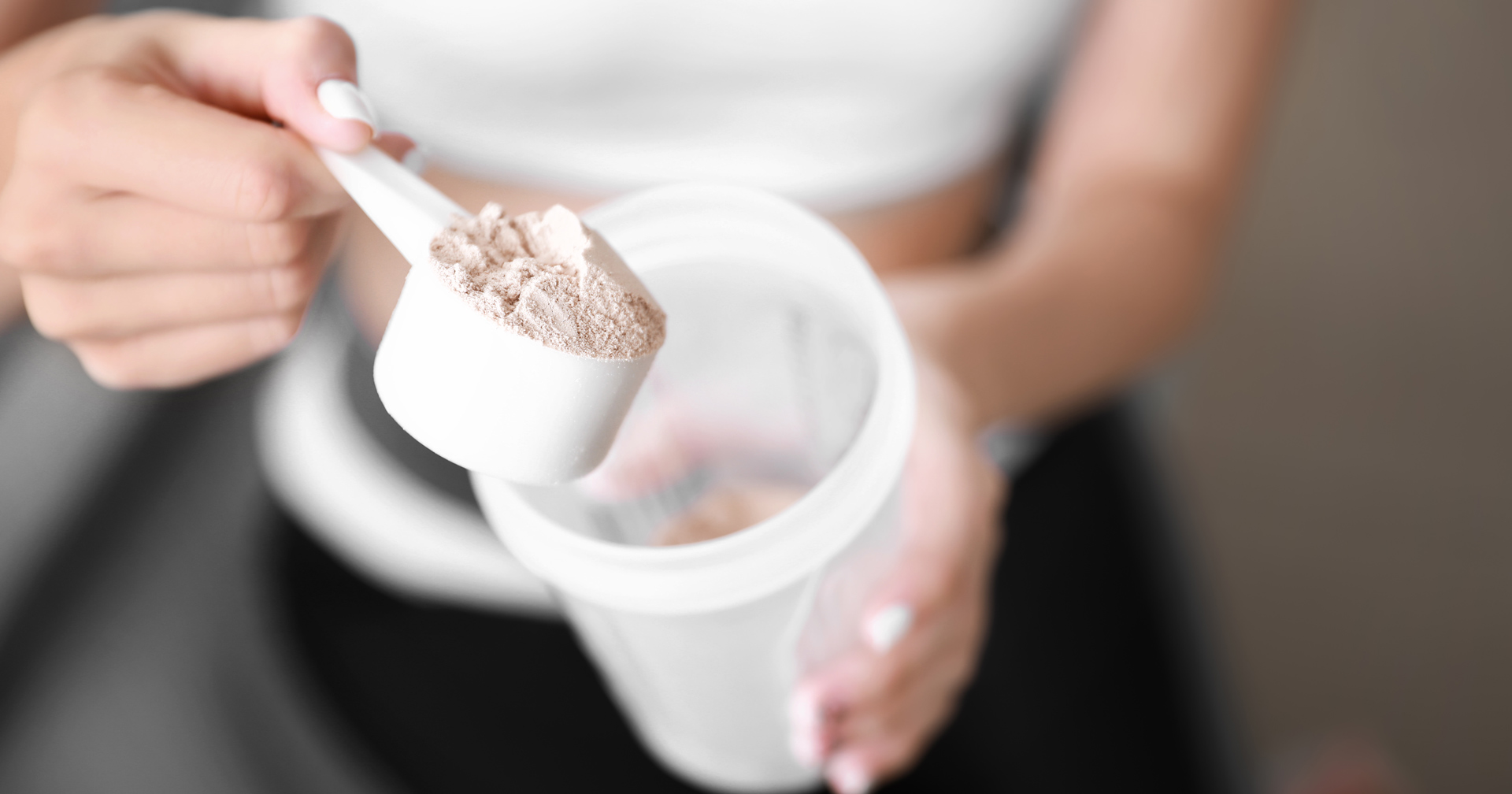 Fitnessstudiomitglied füllt Proteinpulver in ihren Shaker