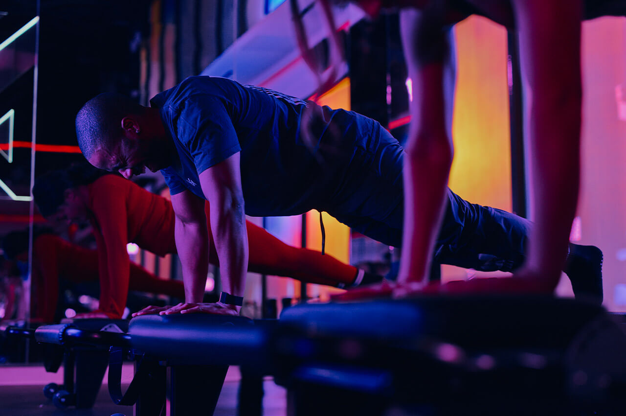 Das Ziel ist ein belastbares, langfristiges Netzwerk von Fitness- und Wellnessmarken in ganz Deutschland Mann in Liegestützposition in Neonlicht