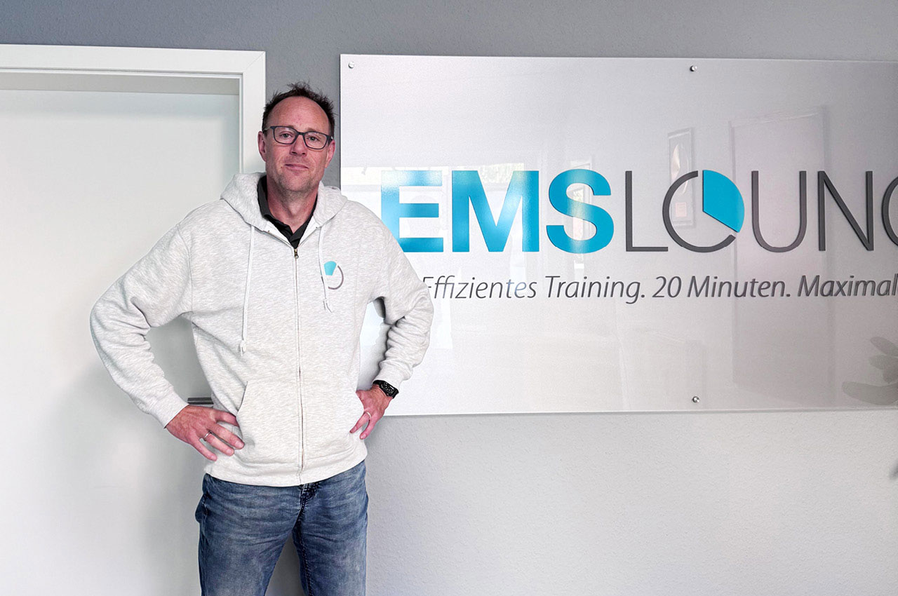 Lars Lüthans steht vor dem Unternehmensschild der EMS-LOUNGE.