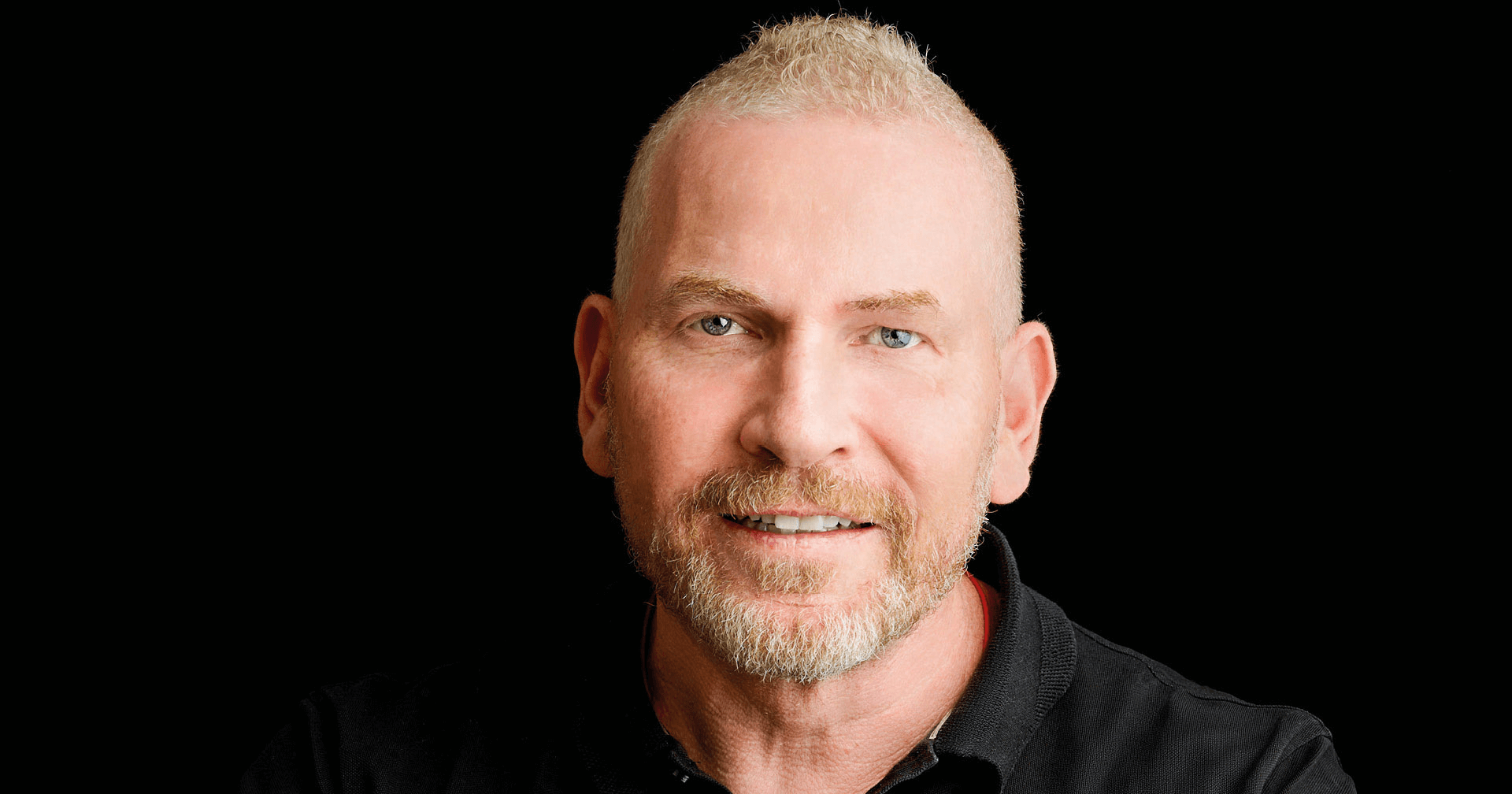 Martin Limbeck steht vor einem schwarzen Hintergrund und blickt nach voren.