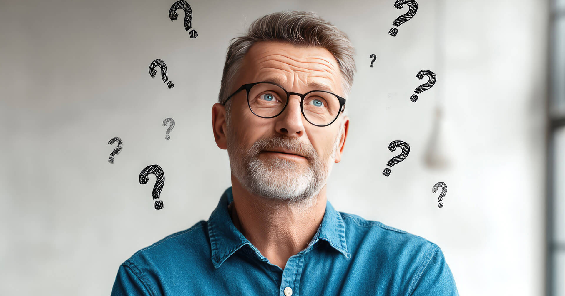 Nahaufnahme eines älteren Mannes mit Brille, grau meliertem Haar und Bart, der in die Ferne blickt und nachdenklich oder fragend dreinschaut. Um seinen Kopf herum sind mehrere gezeichnete schwarze Fragezeichen (?) in verschiedenen Größen eingeblendet. Er trägt ein blaues Hemd.