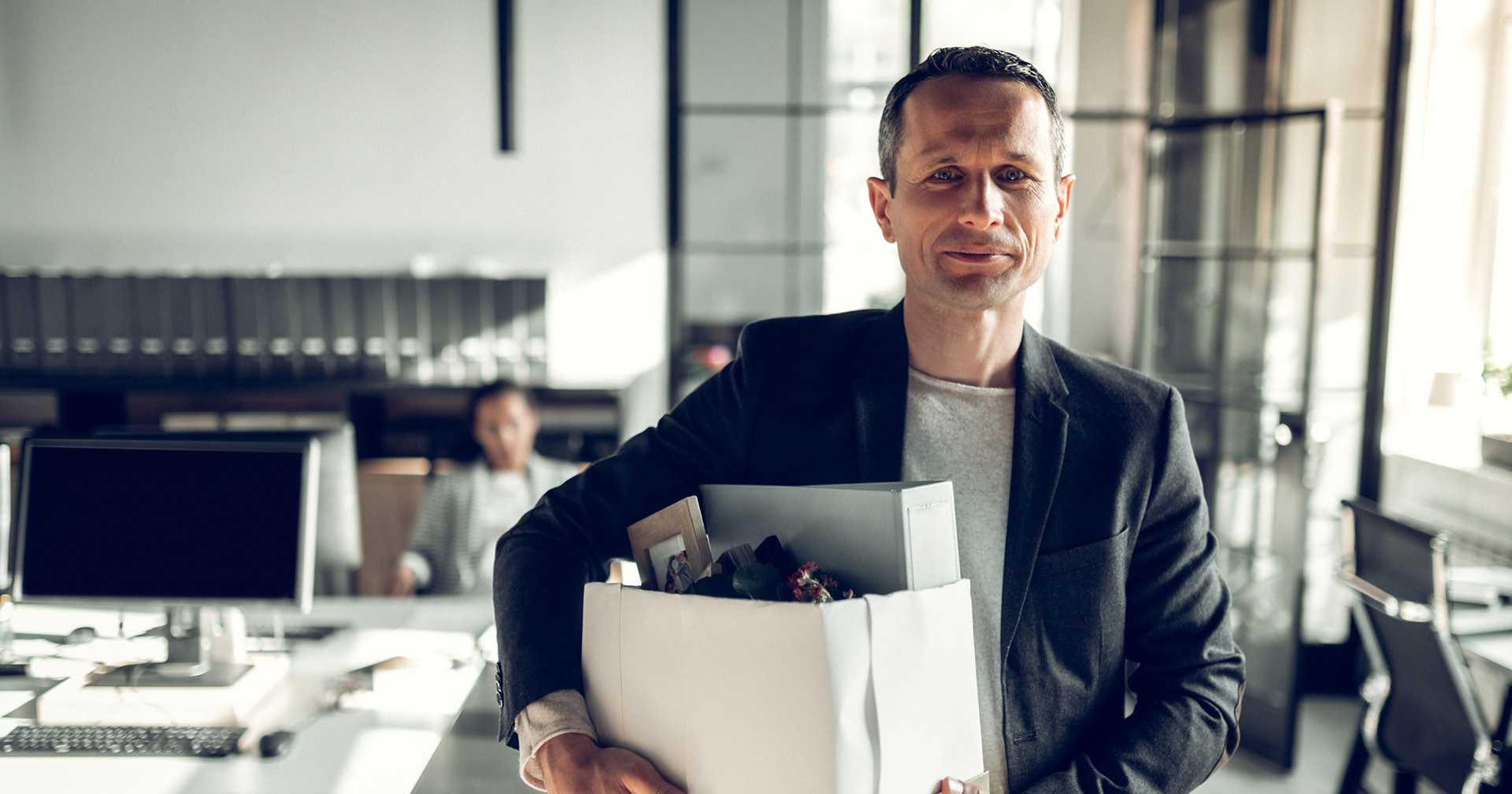 Mitarbeiter verlässt mit einer Box seiner Privatsachen sein ehemaliges Unternehmen