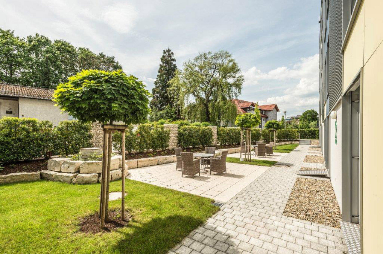 Ein Garten und die Außenbestuhlung der Geriatrischen Reha Klinik in Bad Schönborn ist zu sehen. 