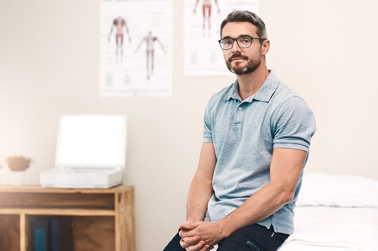 Physiotherapeut sitzt auf Therapieliege