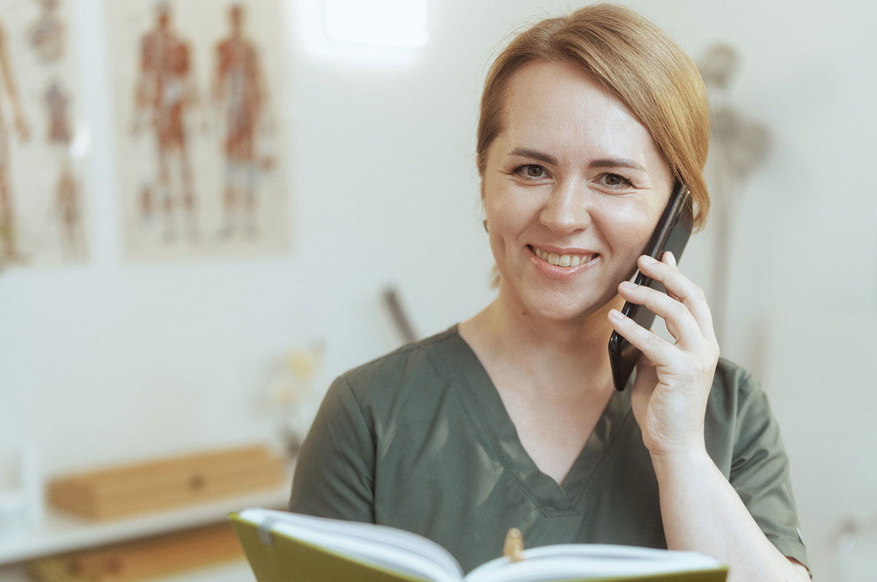 Eine Physiotherapeutin hat ein Telefon in der Hand und telefoniert.