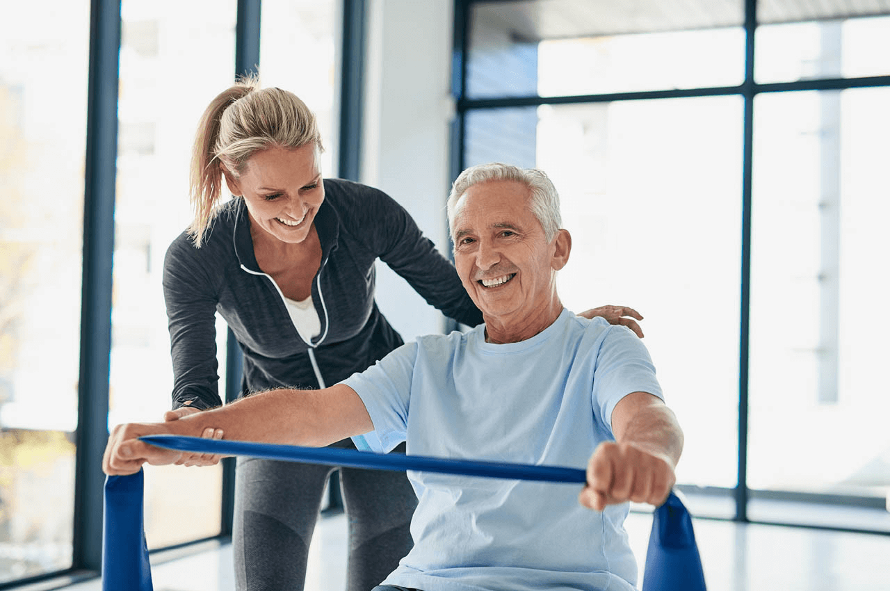 Eine Physiotherapeutin ist neben ihrem Patienten, der eine Übung ausführt.