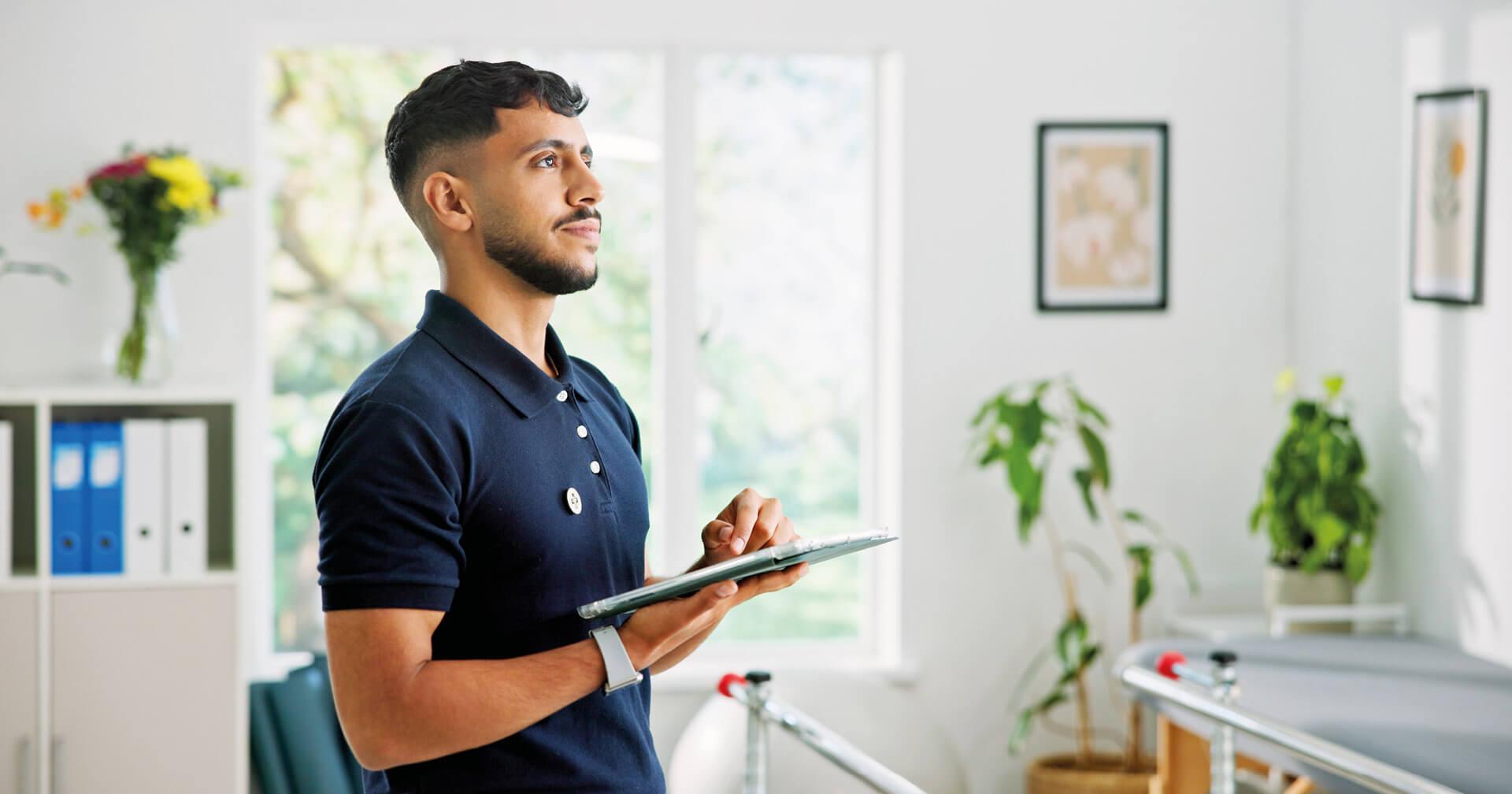 Physiotherapeut mit Tablet in der Hand in einer Praxis