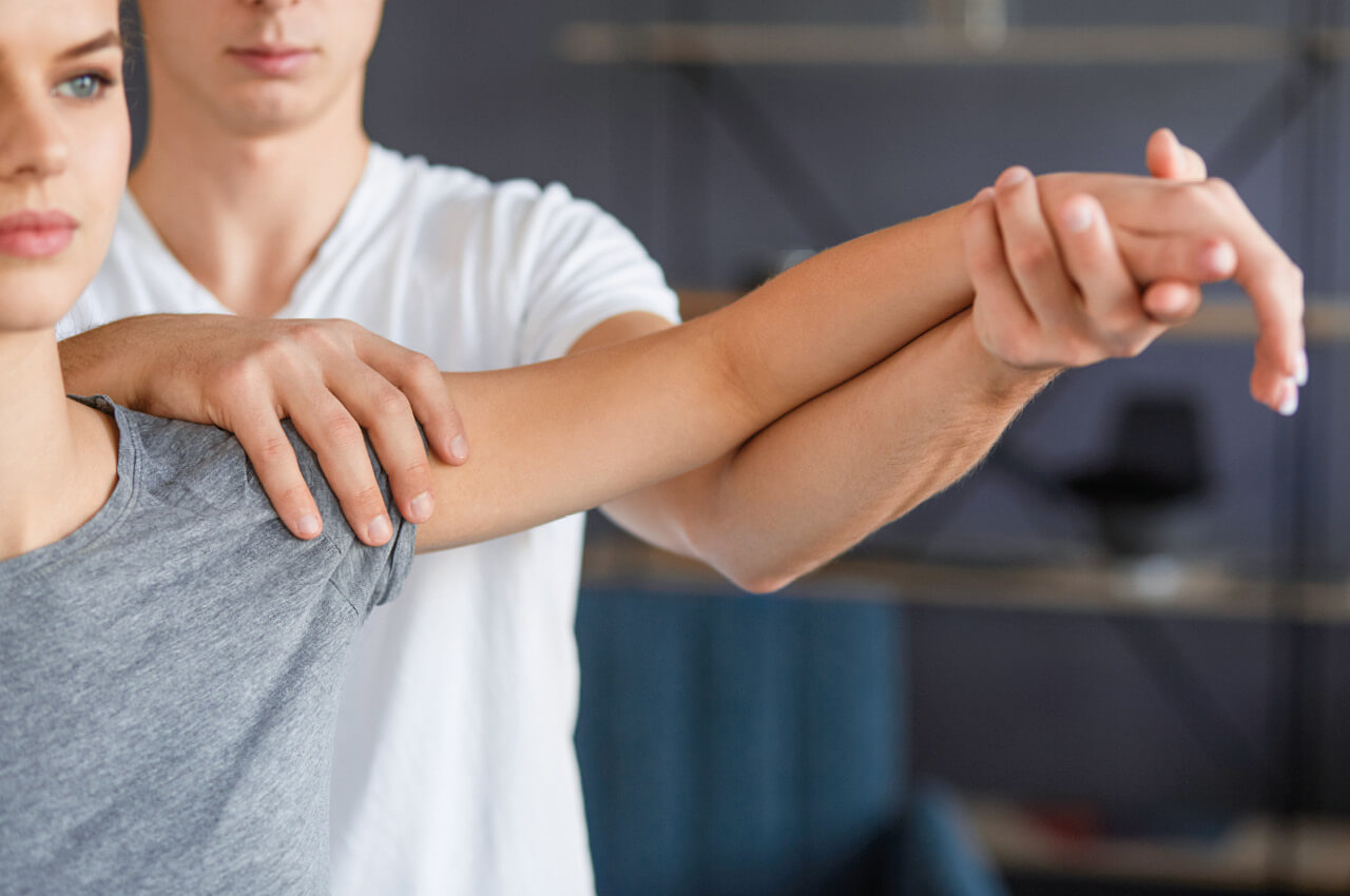 Physiotherapeut behandelt Arm einer Patientin