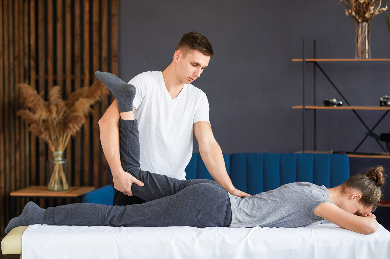 Physiotherapeut behandelt Bein einer Frau 
