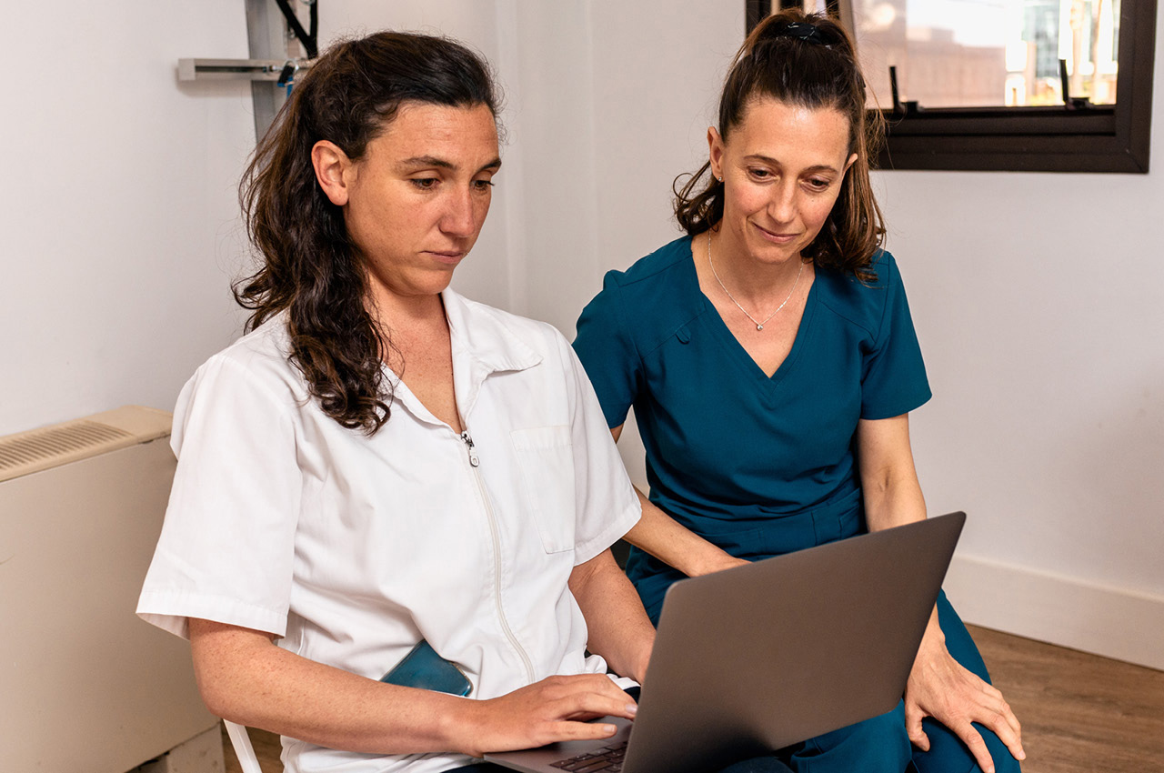 Zwei Physiotherapeuten sitzen und rechts davon hält die Vorgesetzte einen Laptop auf dem Schoß.