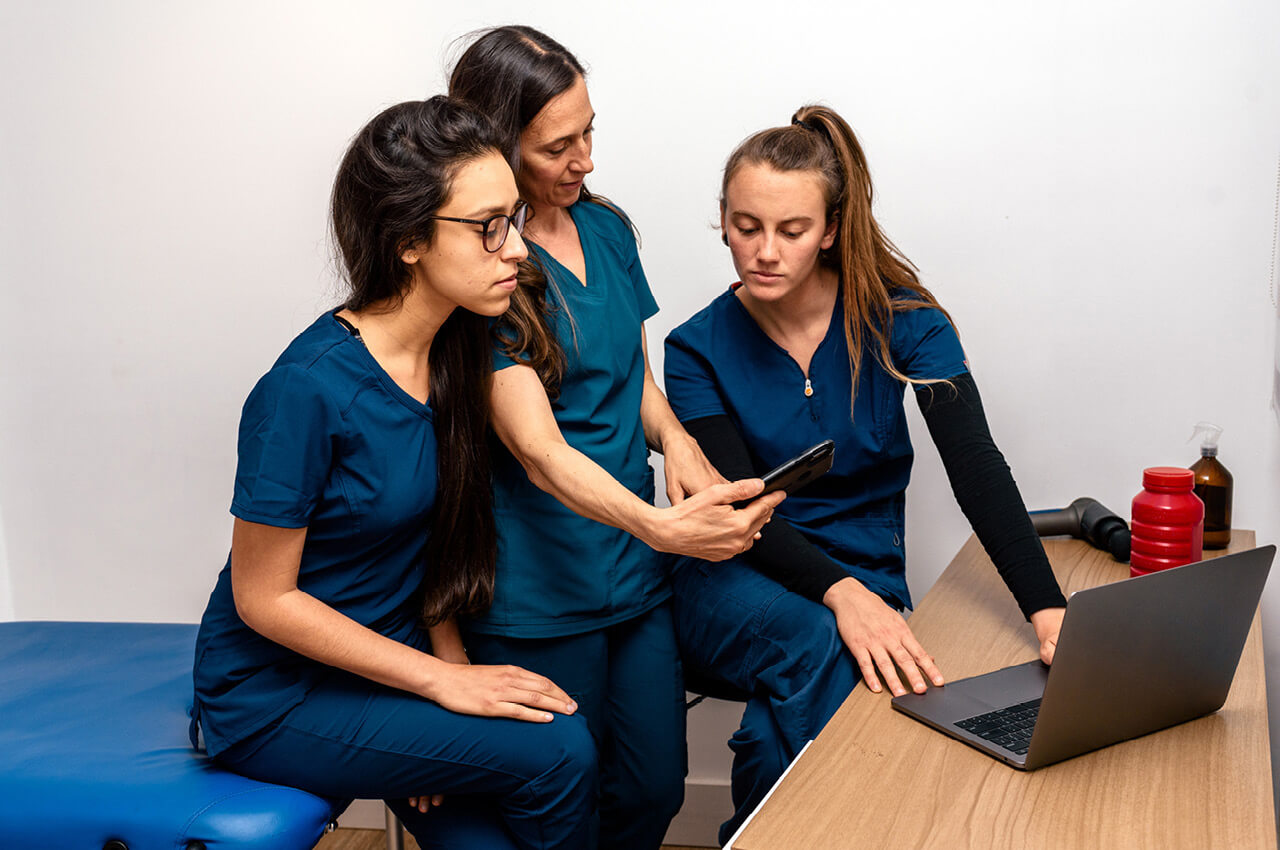 Drei Physiotherapeutinnen blicken auf ein Tablett.